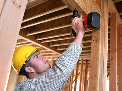 Construction worker operating cordless power drill